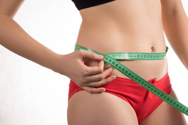 Menina em uma dieta medindo cintura e abdômen centímetro e olha
  - Foto, Imagem
