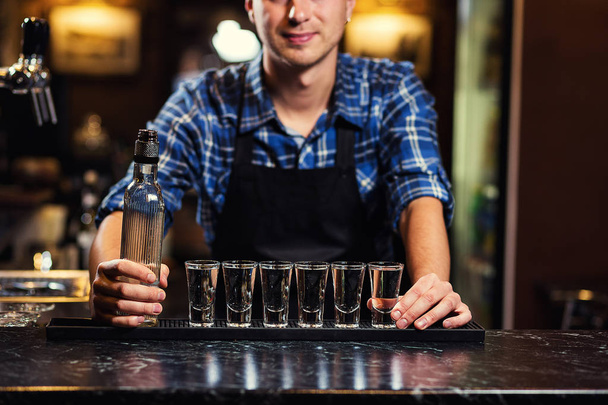 Barman en el trabajo, Barman vertiendo espíritu duro en los vasos en detalle, Bartender está vertiendo tequila en el vidrio, preparando cócteles, concepto de servicio
  - Foto, imagen