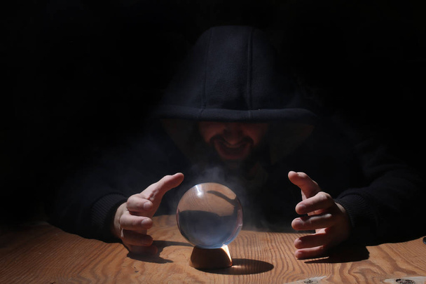 man in a black hood with cristal ball - Photo, Image