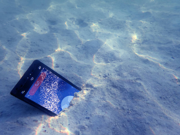 海の水の下で携帯電話. - 写真・画像