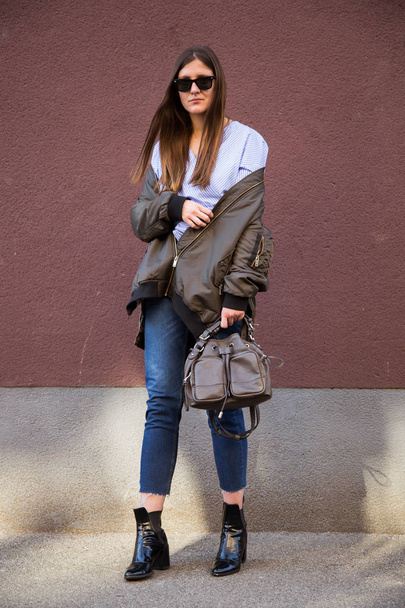 perfect spring fashion outfit. european fashion blogger wearing sunglasses, a trendy crossover striped blouse with a front knot and a bomber jacket. wind in hair. - Φωτογραφία, εικόνα