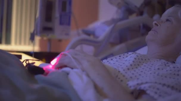 TV knippert in donkere ziekenhuis kamer terwijl patiënt horloges - Video