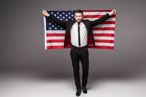 Hombre de negocios con traje sosteniendo la bandera de EE.UU. de la espalda con la boca abierta
 - Foto, imagen