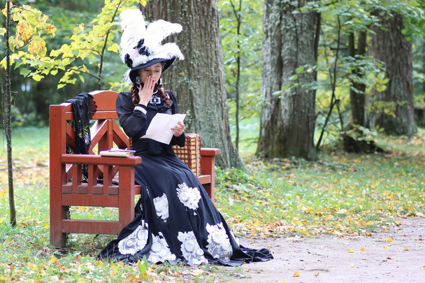レトロなドレスの女の子過去世紀はベンチで手紙を読む - 写真・画像