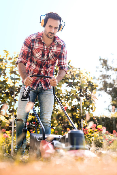 Hombre cortando hierba en su patio
 - Foto, imagen