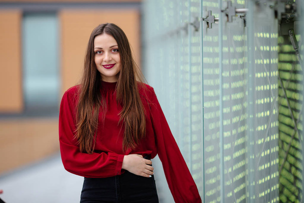Young business woman standing near wall and smile to camera - Foto, afbeelding
