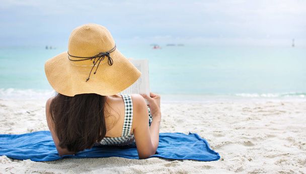 Chica leyendo un libro en una playa de arena
 - Foto, Imagen