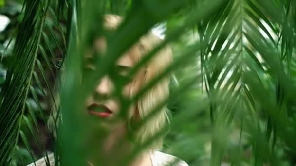 Gentle portrait of blonde woman in tropical botanical garden - Felvétel, videó