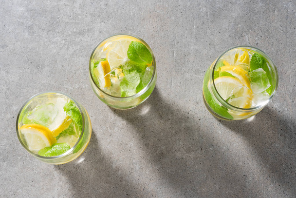 Refreshing lemonade with mint leaves and ice on gray stone table - Foto, afbeelding