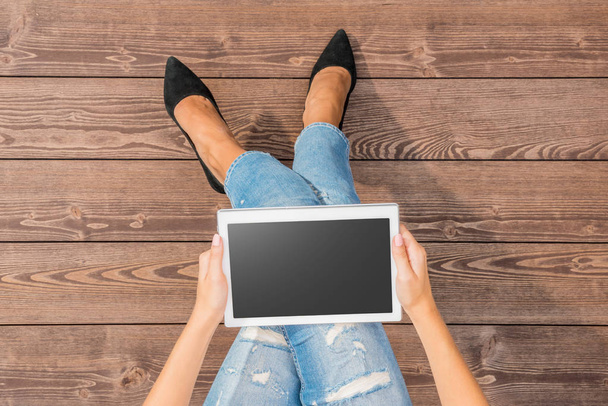 Fashionable woman using tablet over wooden floor - Фото, изображение