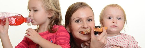 Nuori äiti ja hänen pienet tyttärensä syövät pizzaa ja pitävät hauskaa
 - Valokuva, kuva