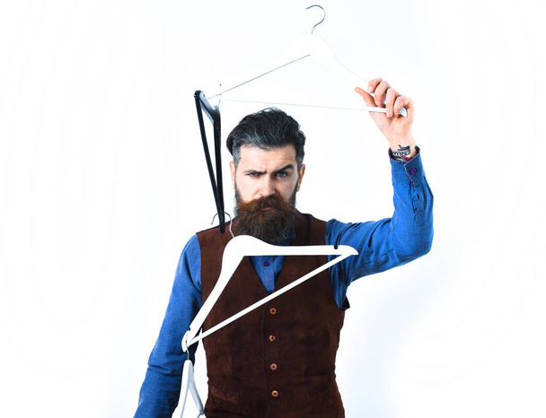 bearded man holding clothes racks with serious face - Zdjęcie, obraz
