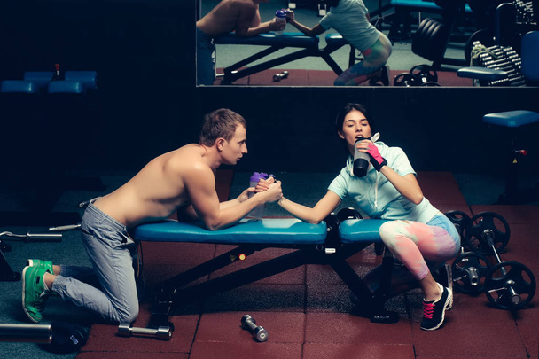 arm wrestling muscular man and girl at gym - Фото, изображение