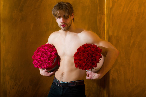 bearded muscular man with sexy body holds red rose box - Фото, изображение