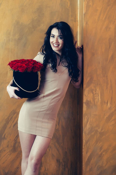 Chica bastante feliz sonriendo con rosas rojas en la caja
 - Foto, Imagen