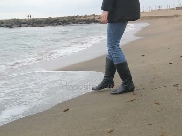 Nő játszik a tenger hullámai a hideg jeges strandon - Felvétel, videó
