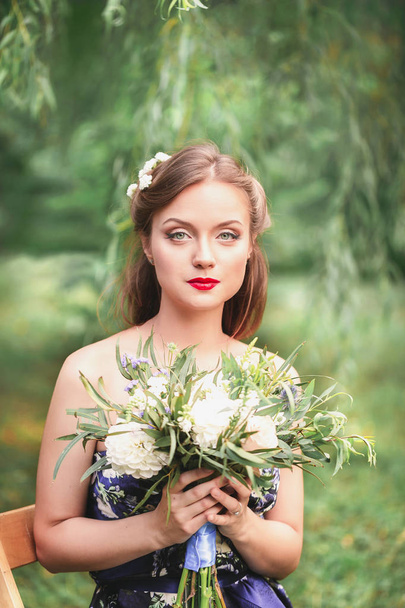 beautiful young woman with a bouquet of flowers in their hands - Photo, Image