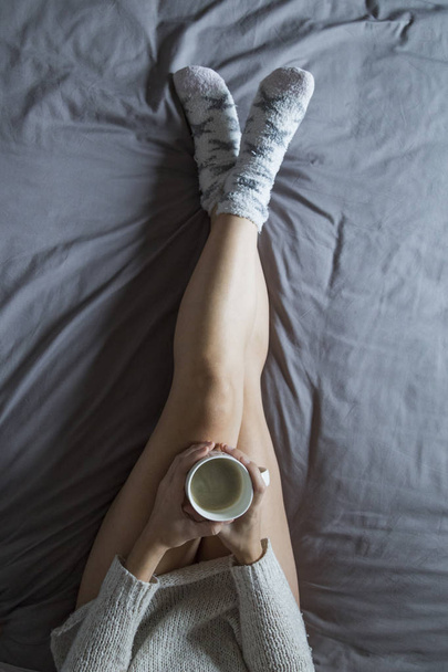 beautiful young woman enjoying coffee on bed in her bedroom. hom - Foto, afbeelding