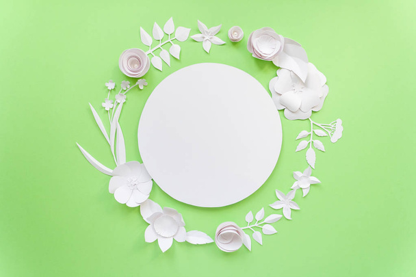 Round frame with white paper flowers on green background. - Zdjęcie, obraz