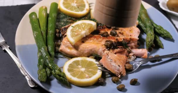 Sprinkling black pepper over a roasted organic salmon with capers and dill - Footage, Video