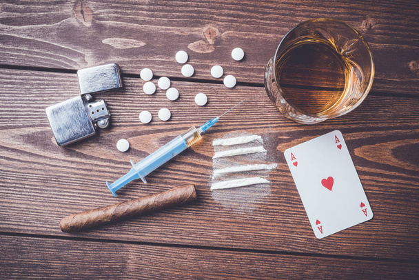 Hard drugs with pills, playing cards, syringe and alcohol on wooden table - Φωτογραφία, εικόνα