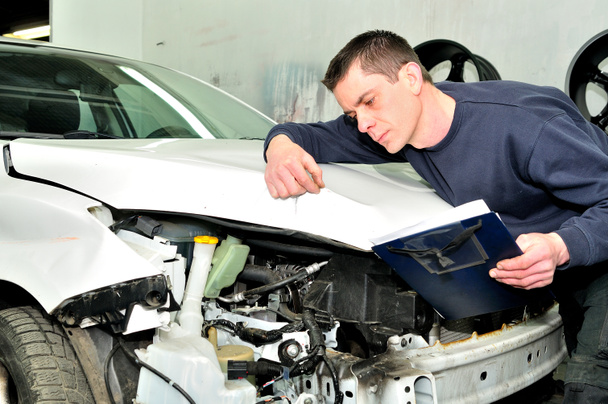 Mecánico de inspección de daños en el cuerpo del coche en el servicio de taller de reparación de automóviles
  - Foto, imagen