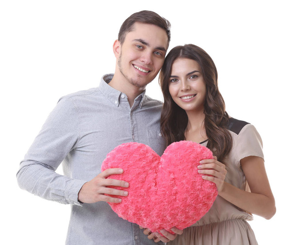 Beautiful young couple with pillow in heart shape on white background - Photo, image
