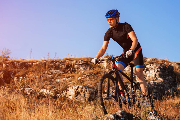 Ciclista profissional montando a bicicleta no Rocky Trail. Esportista no capacete e óculos de sol
. - Foto, Imagem