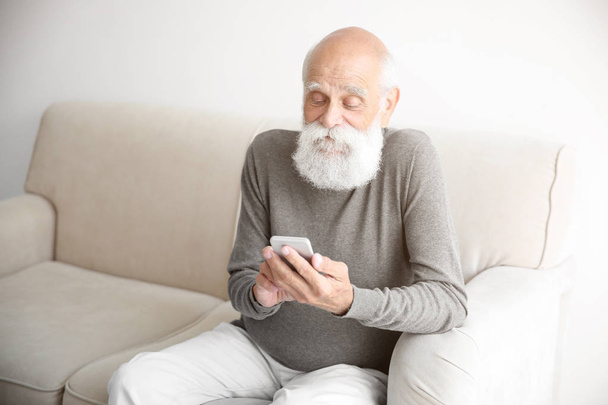 Senior man  with smartphone in room - 写真・画像
