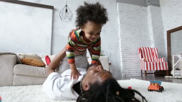 Happy father raising his cute son up at home - Felvétel, videó