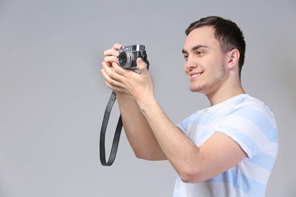 Handsome young tourist taking photo on grey background - Zdjęcie, obraz