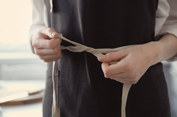 Woman  tying up her apron around the waist - Foto, afbeelding