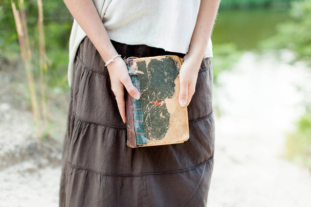 A young girl is holding a very old shabby book in her hands. Sum - Foto, Imagen