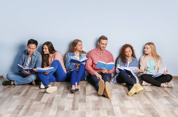 Group of people with books sitting on floor near light wall - Foto, imagen