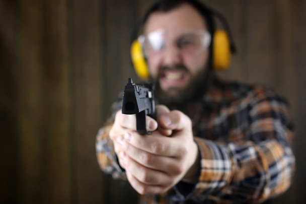 Mann mit Schutzbrille und Gehörbildung in Pistole - Foto, Bild