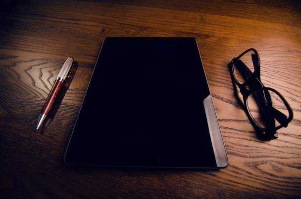 Cellphone, tablet, laptop with glasses and pen. Natural wooden table. Office background. Concept of technology - Foto, Bild