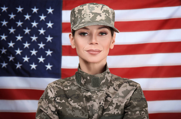 Portrait of female soldier with USA flag on background - 写真・画像