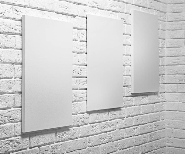 Empty canvases on white brick wall  - Foto, imagen