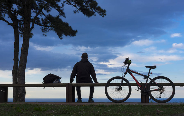 Cycliste assis en profitant du coucher du soleil
 - Photo, image