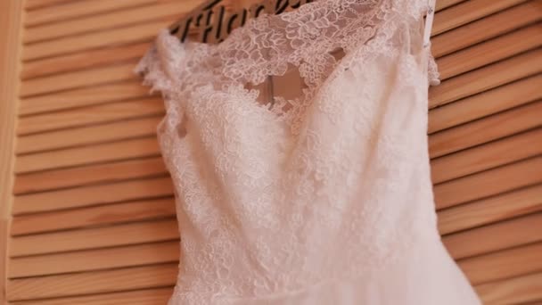 Mooie luxe trouwjurk op hanger op houten achtergrond. Wedding voorbereiding - Video