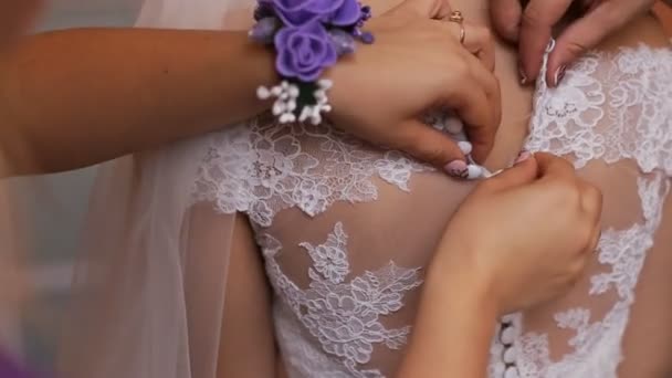Bruidsmeisjes handen dichtknopen op mooie bruid trouwjurk. Close-up - Video