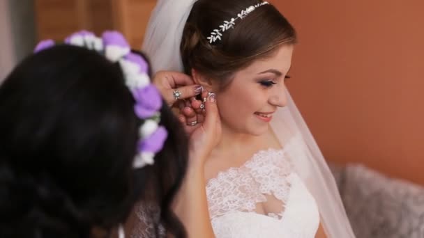 Bridesmaid helping bride to dress up before wedding ceremony. Hooking earrings - Footage, Video