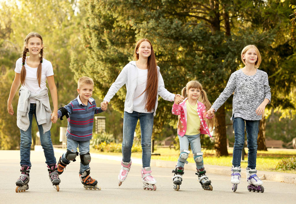 Cheerful children on roller skates in park - Foto, afbeelding