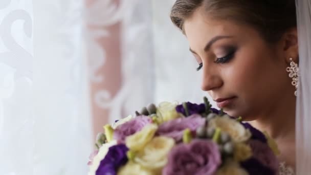 Όμορφη νύφη μυρίζοντας γαμήλια ανθοδέσμη λουλουδιών και εξετάζοντας τη φωτογραφική μηχανή. Κοντινό πλάνο - Πλάνα, βίντεο