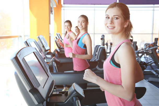 Young sporty women running on treadmills in gym - Fotó, kép
