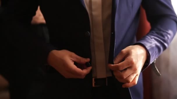 Groom buttoning up his dark blue jacket before wedding ceremony. Close up. Soft light - Footage, Video