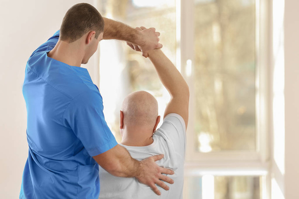 Physiotherapist working with elderly patient in clinic - Foto, Bild