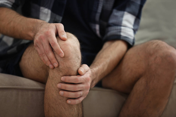 Muž trpící bolestí kolena doma, detailní záběr - Fotografie, Obrázek