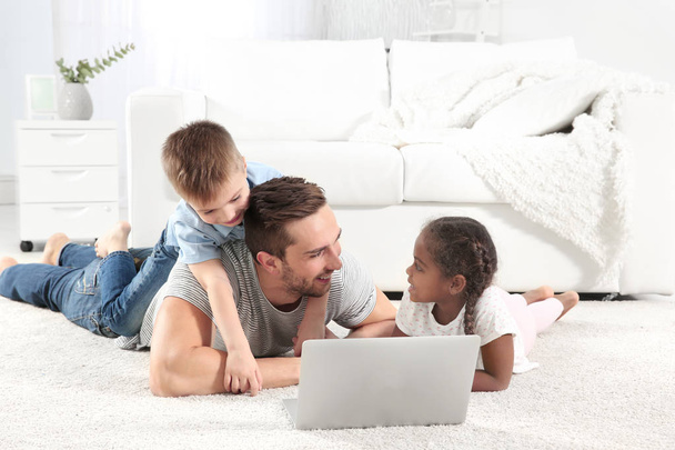 father with children lying with laptop - Foto, imagen