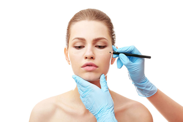 Plastic surgeon drawing line on face - Foto, afbeelding